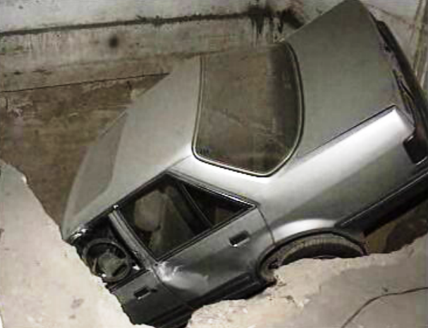 Carro cai em buraco no interior de uma garagem