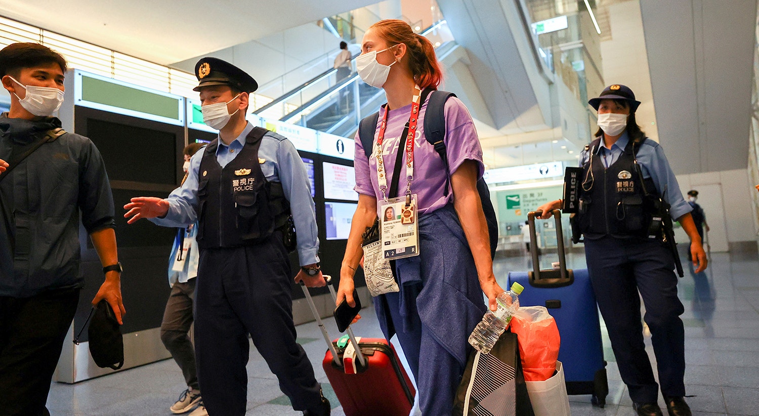  A atleta bielorrussa Krystsina Tsimanouskaya escoltada pelas autoridades japonesas no aeroporto, aquando o seu pedido de asilo. | Foto: Issei Kato - Reuters 
