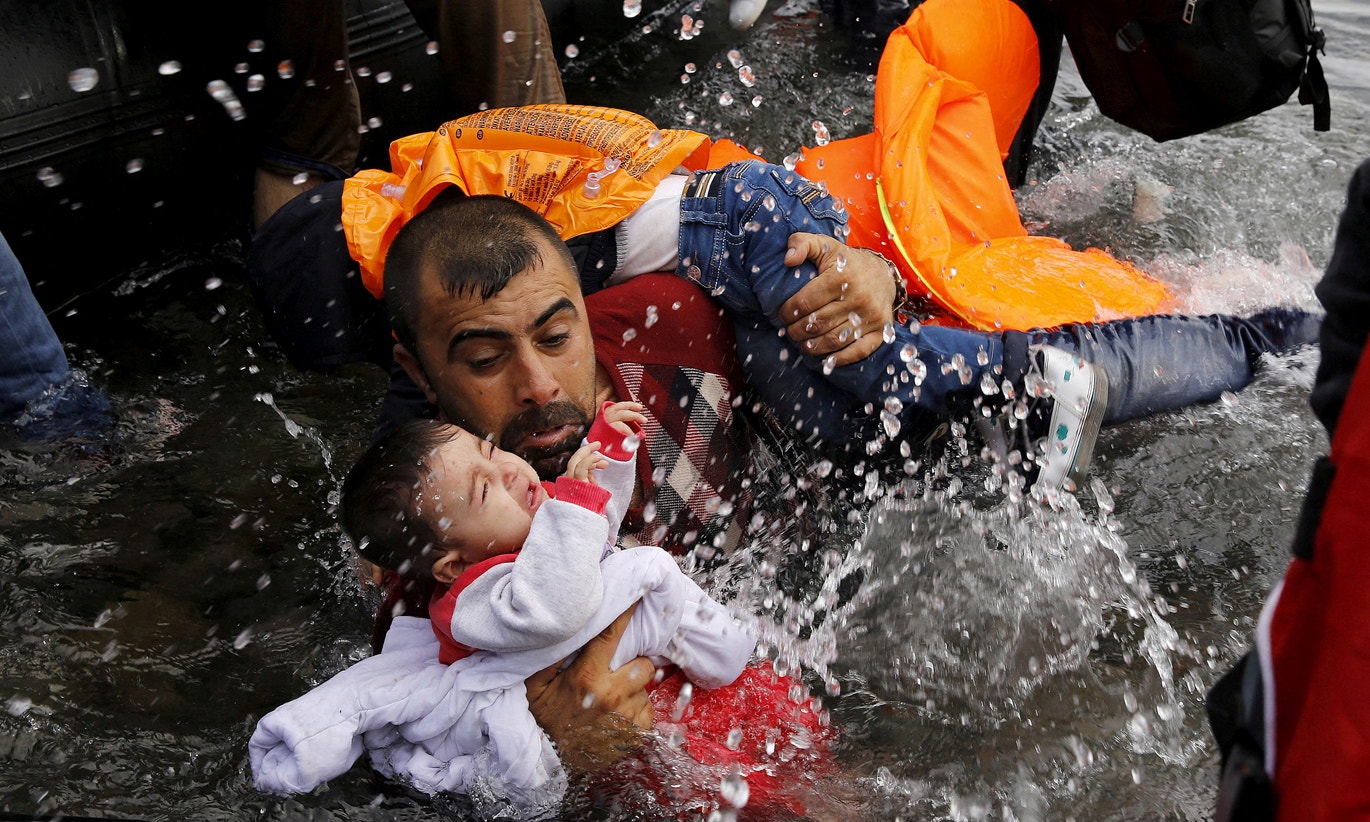  Resgate de migrante s&iacute;rio que carrega duas crian&ccedil;as, Ilha de Lesbos, 2015 | Yannis Behrakis - Reuters 