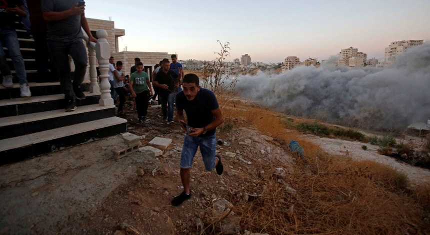 Residentes fogem das explosões provocadas pelas forças israelitas, na aldeia de Sur Baher, no extremo Leste de Jerusalém.
