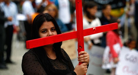 Jovem crist&atilde; caldeia iraquiana ergue uma cruz durante um protesto em Berlim contra a persegui&ccedil;&atilde;o da sua comunidade no Iraque pelos radicais sunitas do Estado Isl&acirc;mico (Foto: Reuters)