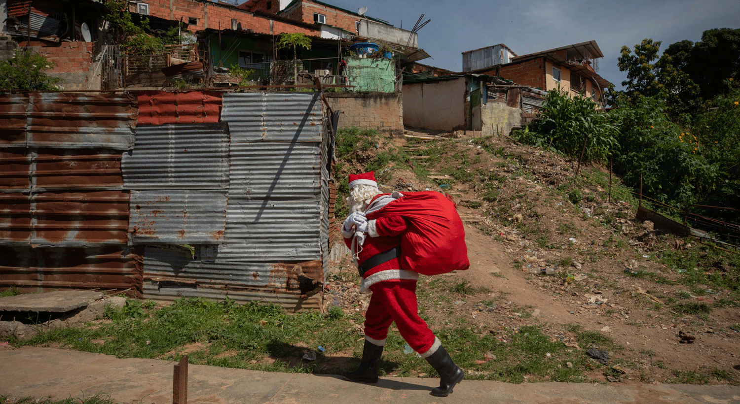  Um jornalista vestido de Pai Natal participa na iniciativa "Um Brinquedo, Boas not&iacute;cias", na &aacute;rea do Cemit&eacute;rio General del Sur em Caracas, Venezuela.  Esta iniciativa de volunt&aacute;rios entregaram presentes a 350 crian&ccedil;as de uma comunidade de Caracas. Cr&eacute;ditos: EPA/Rayner Pena R. 