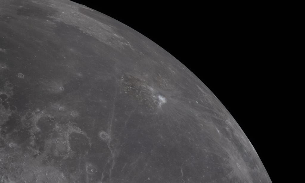  O lado vis&iacute;vel da Lua &eacute; observado atrav&eacute;s da Orion quando se aproximava para o sobrevoo lunar. O lado vis&iacute;vel, caracterizado pelas manchas escuras de lava antiga, &eacute; vis&iacute;vel no ter&ccedil;o superior do disco lunar. A cratera Aristarco &eacute; o ponto branco brilhante em meio a um fluxo de lava cinza-escuro na parte superior da imagem. Cr&eacute;dito: NASA 