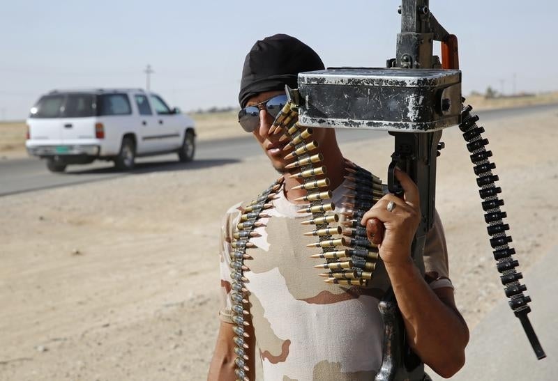 Combatente das Brigadas Badr, xiitas iraquianas, mostra a sua arma num posto de controlo no norte do Iraque Foto: Reuters 