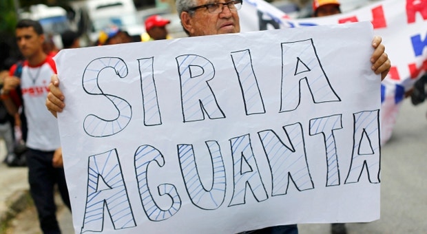 A crise síria movimenta a opinião pública do mundo inteiro. Na foto, um homem segura um cartaz dizendo "Síria aguenta" durante uma manifestação a favor da Síria, em Caracas
