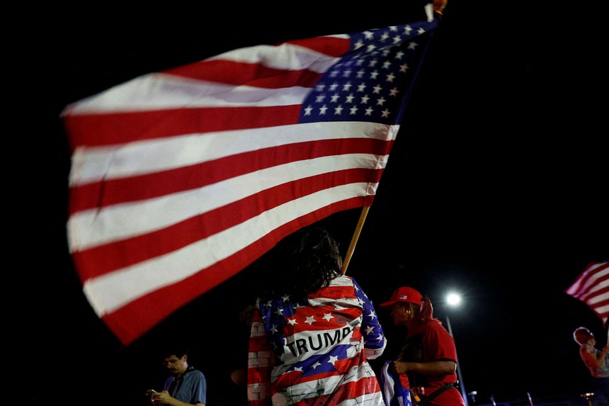 Uma apoiantes de Donald Trump empunha uma bandeira norte-americana momentos após o atentado na Pensilvânia
