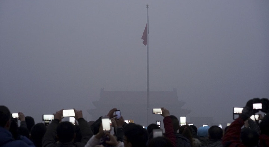 Turistas fotografam e gravam vídeos do içar de uma bandeira na Praça Tiananmen em Pequim no meio de smog intenso
