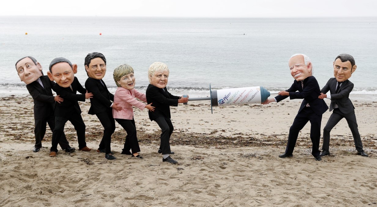  Ativistas da Oxfam com caricaturas de &quot;Cabe&ccedil;udos&quot; retratam os l&iacute;deres dos G7 que fingem lutar por uma vacina COVID-19, durante um protesto  numa praia perto de Falmouth, &agrave; margem da Cimeira | Peter Nicholls - Reuters 