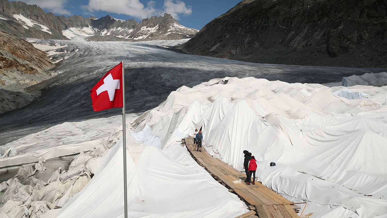  Pessoas visitam a caverna de gelo coberta com material para evitar que o gelo derreta, no Glaciar Rhone na Furka, Su&iacute;&ccedil;a, 21 de agosto de 2019. | Denis Balibouse - Reuters 
