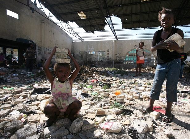  Duas crian&ccedil;as ajudam a remover pedras do que era antes do terramoto o mercado de Petionville 