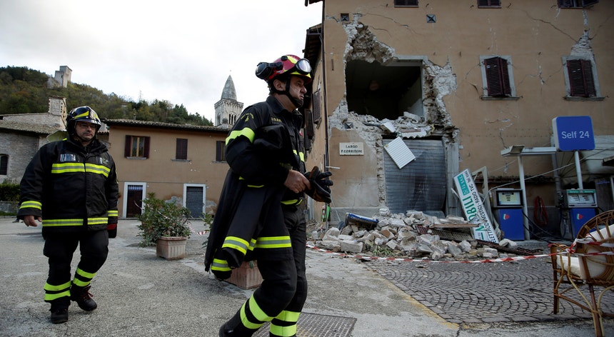 Dois socorristas em torno de um edifício destruído após os sismos de Visso
