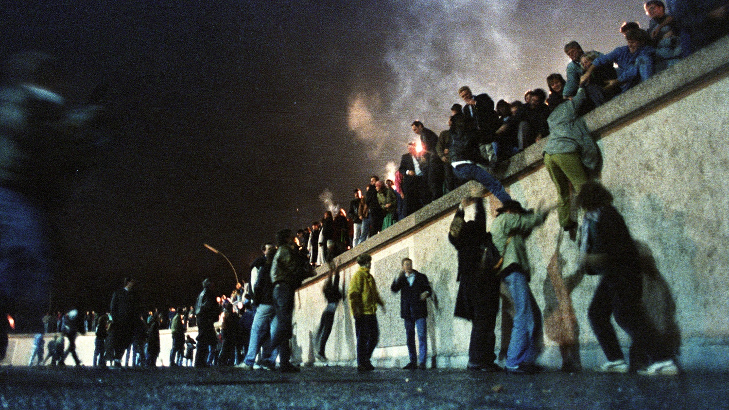  V&aacute;rias pessoas do lado ocidental sobem o Muro na porta Brandemburgo, depois do an&uacute;ncio da abertura da fronteira. 9 de novembro de 1989 | Herbert Knosowsk - Reuters 