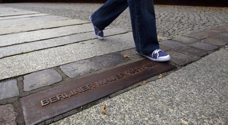 Uma linha de tijolos e uma placa marcam os locais onde se erguia o Muro de Berlim (foto: Thomas Peter/Reuters)