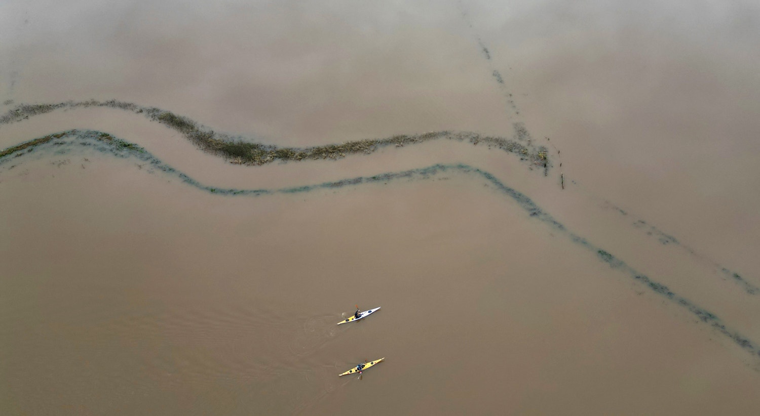  Cano&iacute;stas remam em campos inundados perto de Langport, em Somerset, sudoeste da Gr&atilde;-Bretanha, 15 de dezembro | Toby Melville - Reuters 