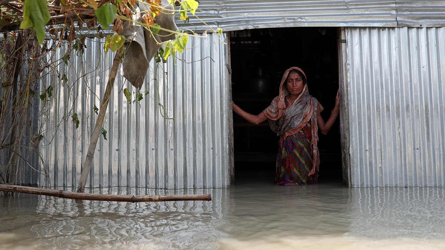  Saju Begum, uma mulher afetada pelas enchentes posa para a fotografia dentro da sua casa em Jamalpur, Bangladesh. 21 de julho de 2019. | Mohammad Ponir Hossain - Reuters 