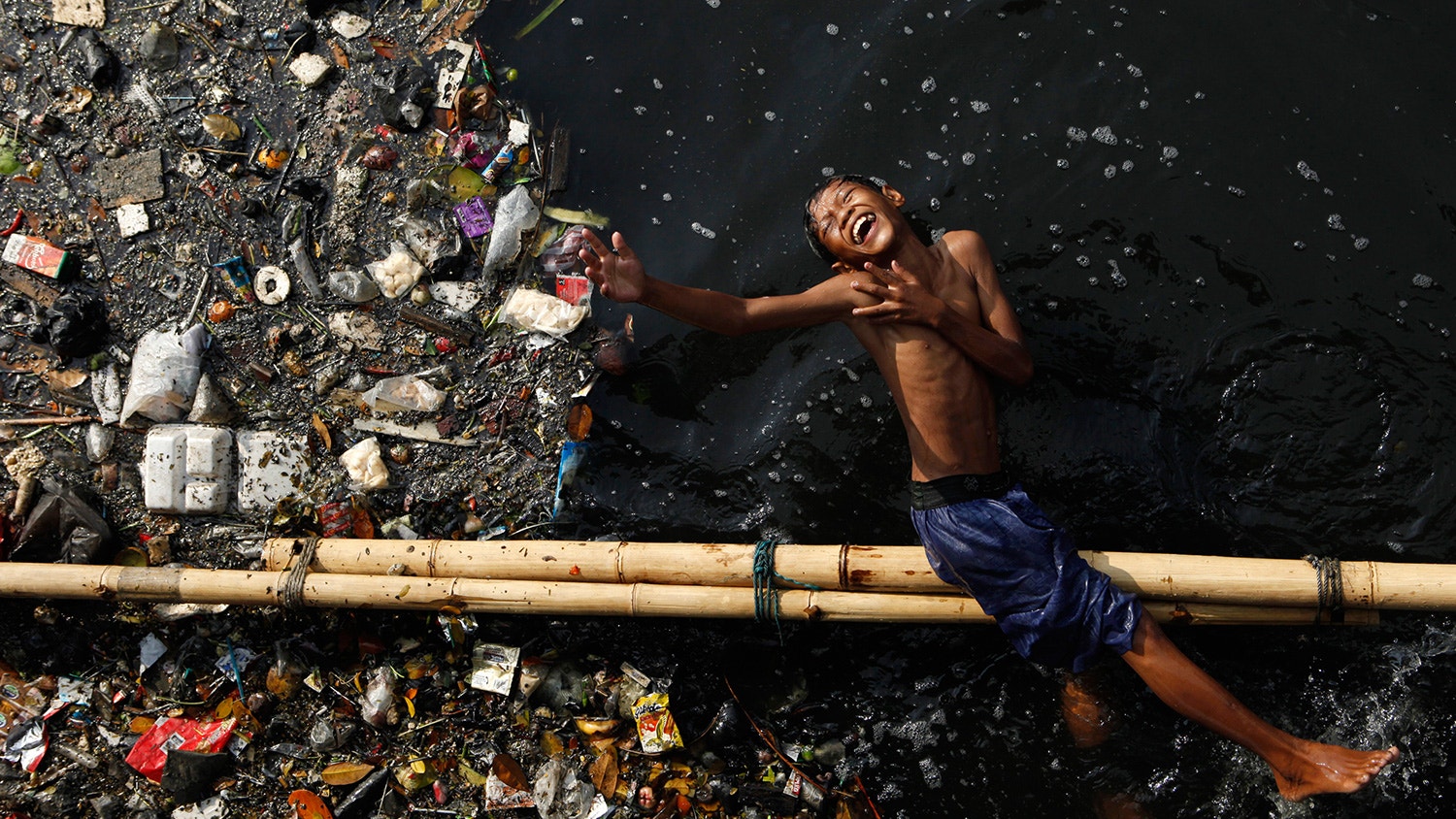  Depois da escola, uma crian&ccedil;a brinca num rio polu&iacute;do em Jacarta, na Indon&eacute;sia. 5 de junho de 2009. | Beawiharta - Reuters 
