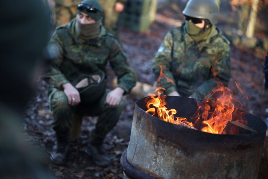 Soldados ucranianos aquecem-se junto a uma fogueira na área de treino especial multinacional do exército alemão Bundeswehr
