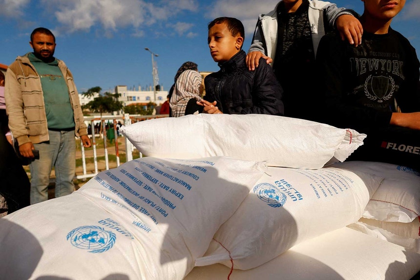 Palestinianos recebem sacos de farinha distribuídos pela Agência das Nações Unidas para os refugiados palestinianos (UNRWA). Fotografia de 21 de novembro de 2023
