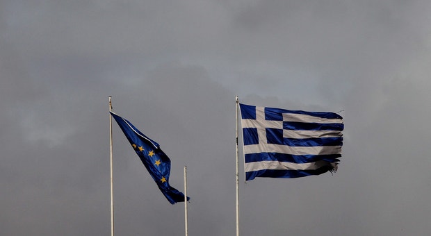Uma bandeira rasgada da UE ondula ao lado de uma desgastada bandeira grega  tendo como pano de fundo um céu carregado de núvens negras. Uma poderosa metáfora da atual situação europeia
