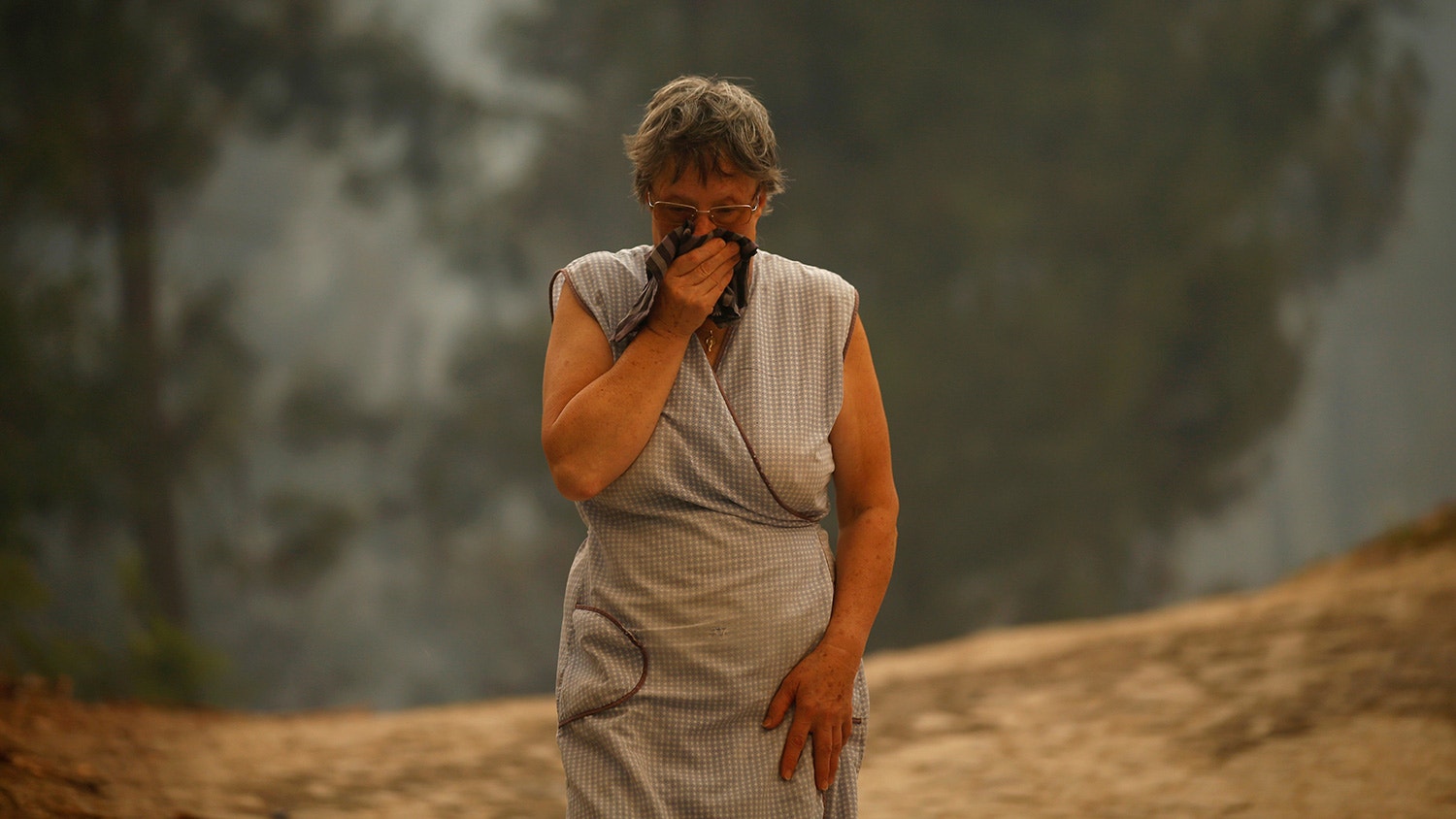  Idosa caminha pelo fumo gerado pelo inc&ecirc;ncio florestal em Oteiro, perto de S&atilde;o Pedro do Sul em Portugal. 13 de agosto de 2016. | Rafael Marchante - Reuters 