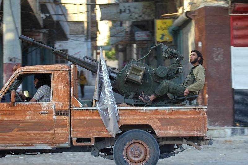 Um militante do grupo rival do Estado Islâmico, Frente al-Nusra, numa carrinha que transporta uma arma anti-aérea em Ariha, Síria Foto: Reuters Um militante do grupo rival do Estado Islâmico, Frente al-Nusra, numa carrinha que transporta uma arma anti-aérea em Ariha, Síria Foto: Reuters