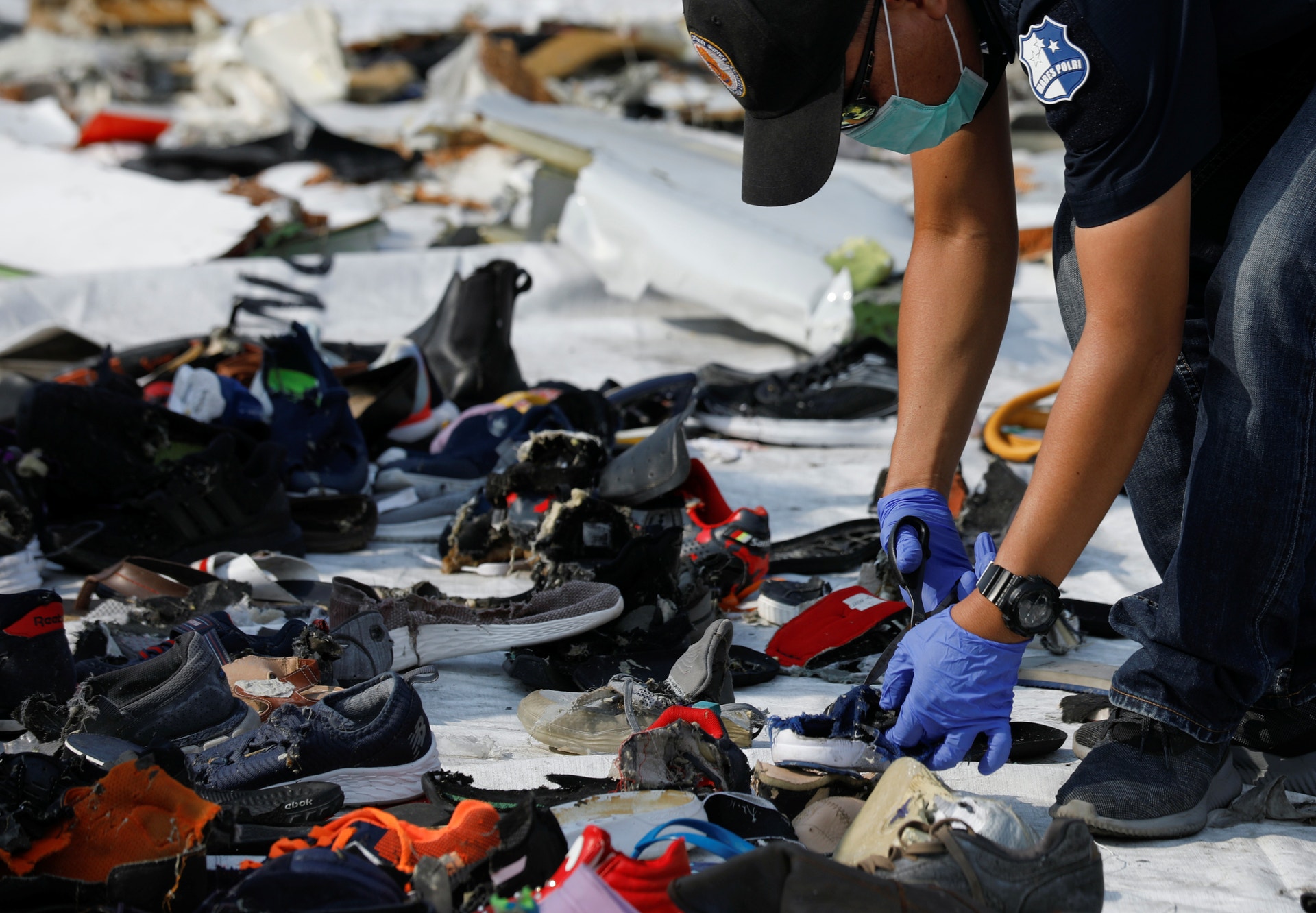  Um investigador recolhe, no local do acidente, os pertences das v&iacute;timas. Foto: Edgar Su  - Reuters 