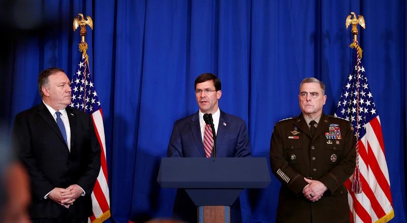 Mark Esper, secretário norte-americano de Defesa, ao centro, com o secretário de Estado, Mike Pompeo, à esquerda, e o general do Exército norte-americano Mark Milley, numa conferência de imprensa sobre o ataque de domingo a várias posições no Iraque e na Síria. 
