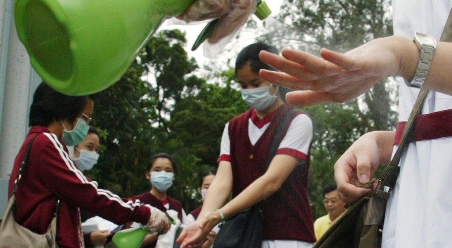  Hong Kong, 2003. Higieniza&ccedil;&atilde;o das m&atilde;os &agrave; entrada das escolas durante o surto de SARS | Bobby Yip - Reuters   