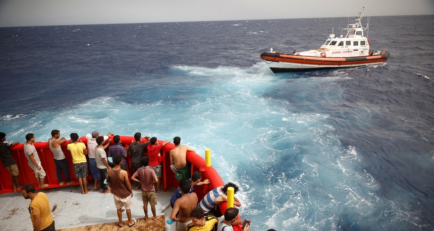 Migrantes a bordo de um barco da ONG Proactiva Open Arms Uno olham para o barco das autoridades italianas que se dirige a Lampedusa | Itália, 19 de agosto de 2022 
