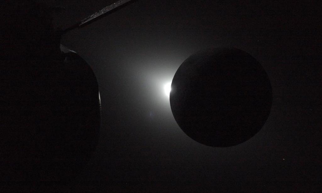  Capturada pela c&aacute;psula Orion, perto do fim do sobrevoo lunar da miss&atilde;o Artemis II no dia 6 de abril, esta imagem mostra o Sol a surgir por tr&aacute;s da Lua enquanto o eclipse transita para fora da totalidade. Apenas uma parte da Lua &eacute; vis&iacute;vel na imagem,  a curva lunar revela uma faixa brilhante de luz solar que regressa aos olhar dos quatro tripulantes ap&oacute;s quase uma hora de escurid&atilde;o. Nos momentos finais do eclipse observados pela tripula&ccedil;&atilde;o, a luz que reaparece cria um forte contraste com a silhueta da Lua e revela a topografia lunar normalmente n&atilde;o vis&iacute;vel ao longo do limbo lunar. Esta fase fugaz captura o alinhamento din&acirc;mico do Sol, da Lua e da sonda enquanto a Orion continua sua jornada de volta do lado oculto da Lua. Cr&eacute;dito: NASA 