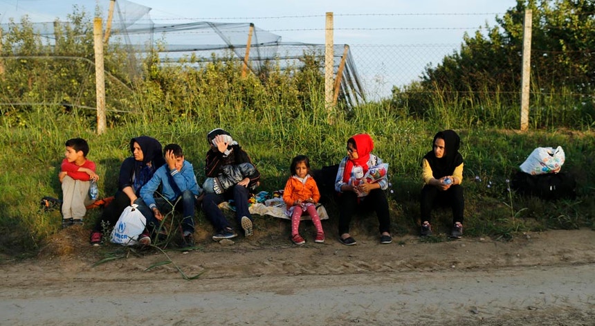 Um grupo de migrantes descansa no caminho perto de Sid, Sérvia, antes de atravessar para a Croácia.
