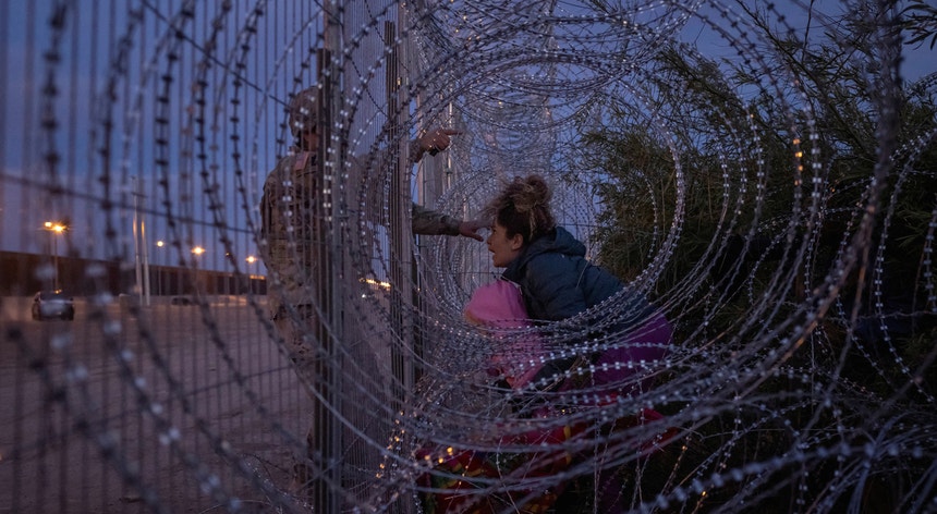 Eliana, de 22 anos, migrante da Venezuela, segura sua filha de três anos, Chrismarlees. Foi travada junto à barreira de arame farpado por um soldado da Guarda Nacional do Exército dos EUA, da margem do rio Rio Grande, em El Paso, Texas
