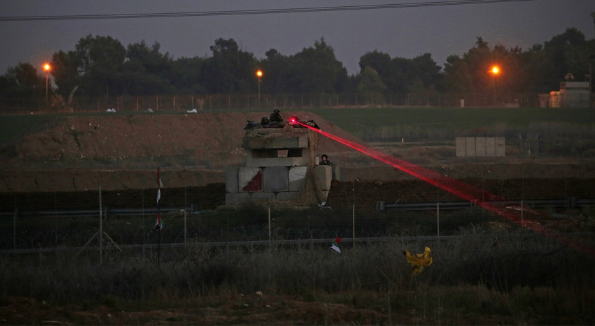 Soldados israelitas aponta uma mira de laser a manifestantes palestinianos na linha de fronteira a leste de Gaza
