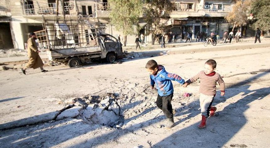 Dois rapazes correm numa zona bombardeada no bairro de al-Shakour, arredores de Aleppo
