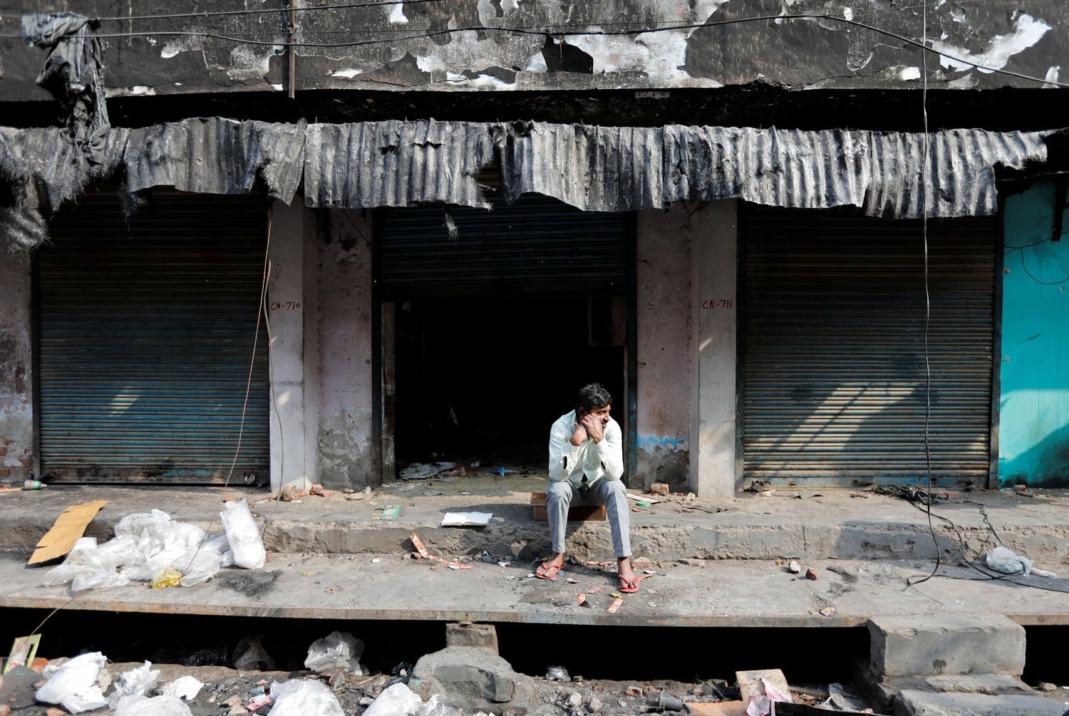 Um homem sentado frente aos restos calcinados de uma loja mu&ccedil;ulmana, incendiada durante manifesta&ccedil;&otilde;es pr&oacute; e contra a nova Lei da Cidadania da &Iacute;ndia, em Nova Deli, a 2 de mar&ccedil;o de 2020 Foto: Reuters