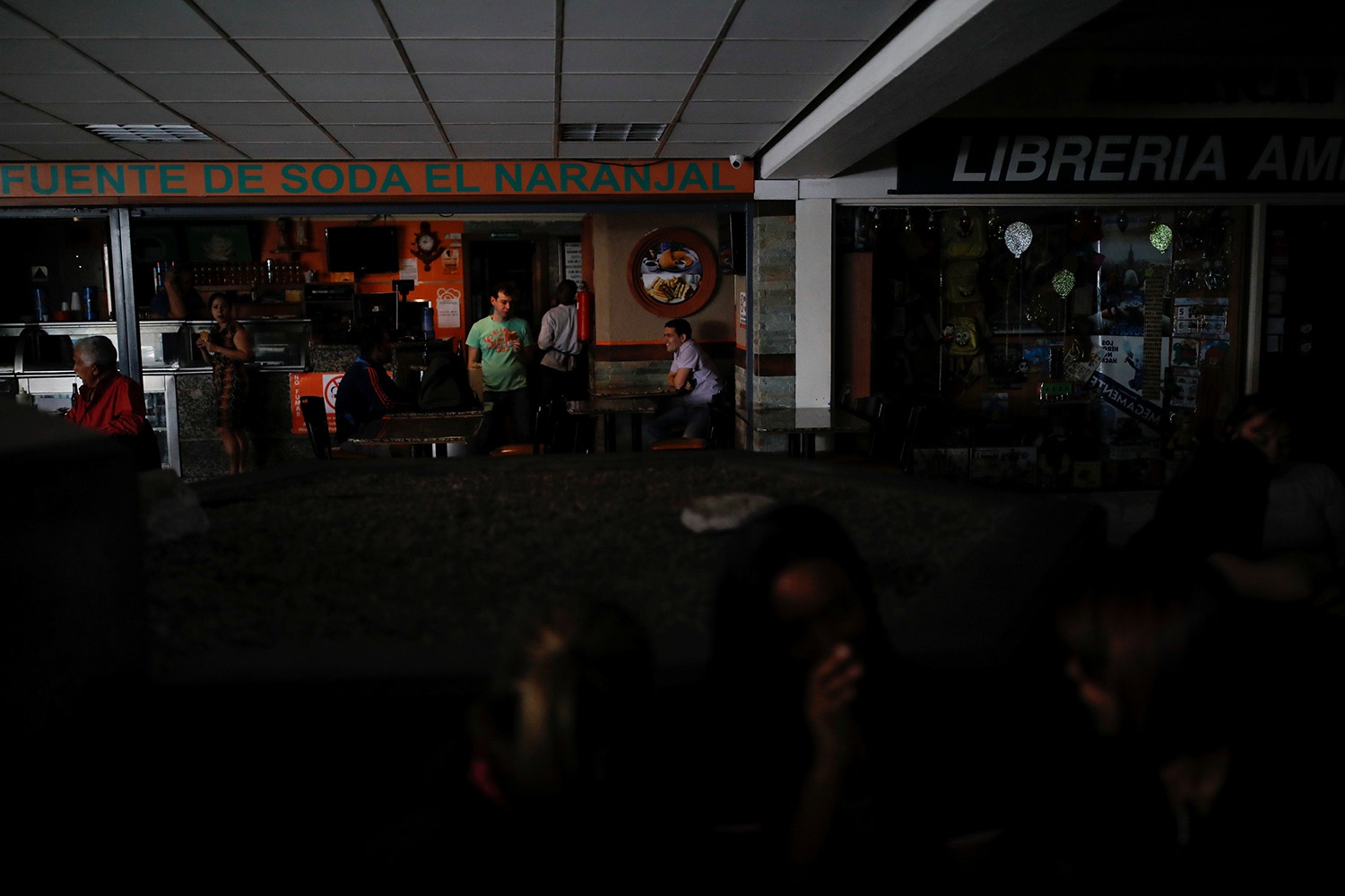  V&aacute;rias pessoas aguardam que a luz seja reposta num centro comercial em Caracas /Foto: Carlos Garcia Rawlins - Reuters 