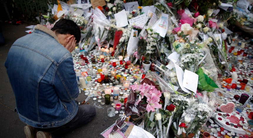 Um homem presta tributo às vítimas dos atentados de Paris junto ao Bataclan.
