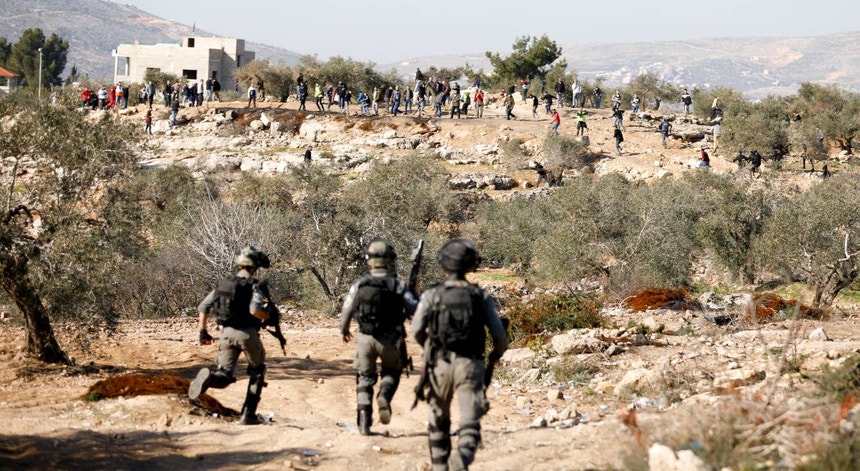 Membros das forças israelitas aproximam-se de um grupo de manifestantes palestinianos durante um protesto contra a ocupação israelita
