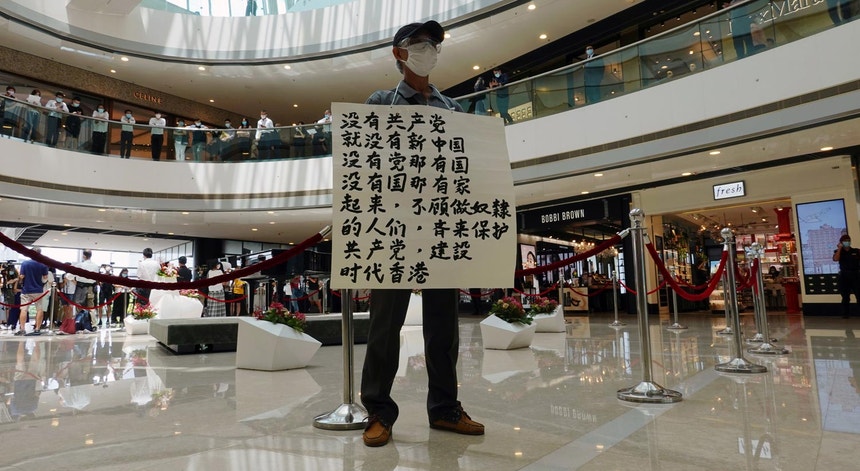 Um homem segura um cartaz num centro comercial de Hong Kong com frases de apoio ao Partido Comunista Chinês, a 6 de julho de 2020. "Sem o Partido Comunista, não existe China", afirma uma das frases

