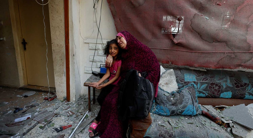 Moradores de uma casa atingida por um ataque aéreo na Faixa de Gaza. 
