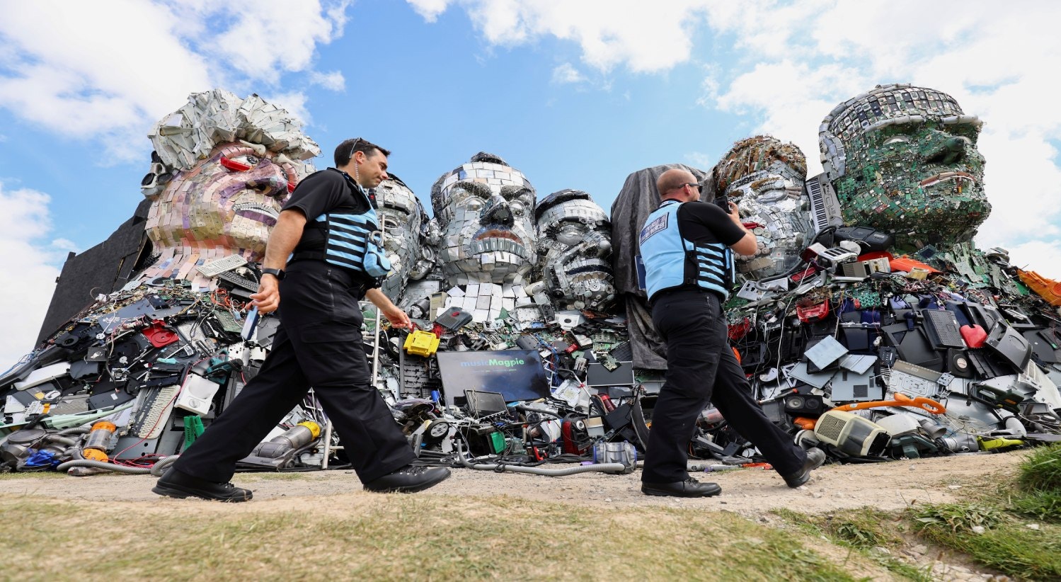  Pol&iacute;cia passa por &quot;Mount Recyclemore&quot;, uma obra de arte que retrata os l&iacute;deres do G7 olhando para Carbis Bay, feita de lixo eletr&oacute;nico por Joe Rush e Alex Wreckage, antes da Cimeira, em Hayle Towans, na Cornualha | Tom Nicholson - Reuters 
