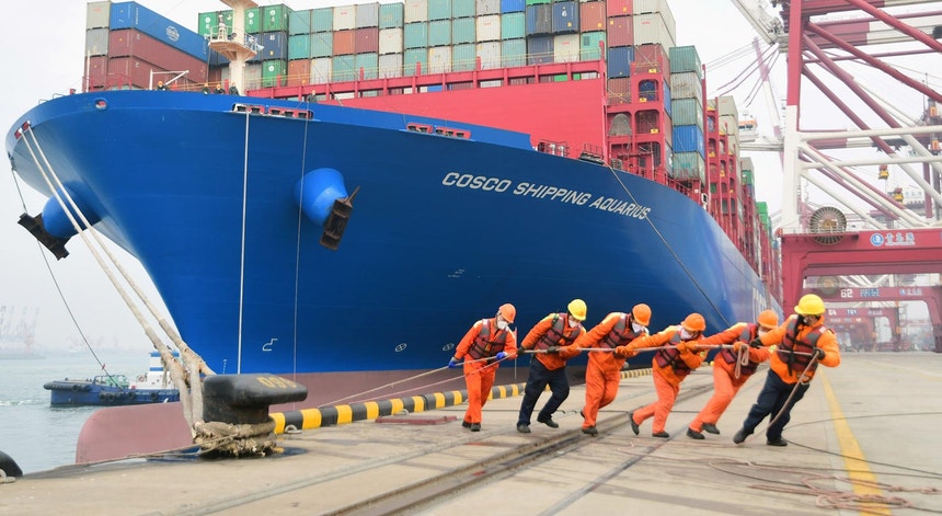 Seis trabalhadores com máscaras puxam um navio contentor no porto de Qingdao, província de Shandong, China, a 11 de fevereiro de 2020.
