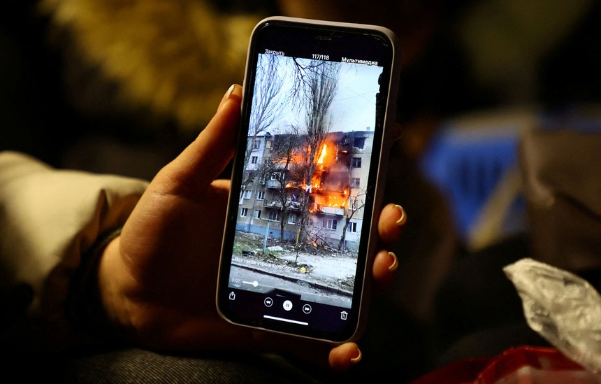 Um edifício bombardeado na Ucrânia pelas forças russas filmado através de um telemóvel
