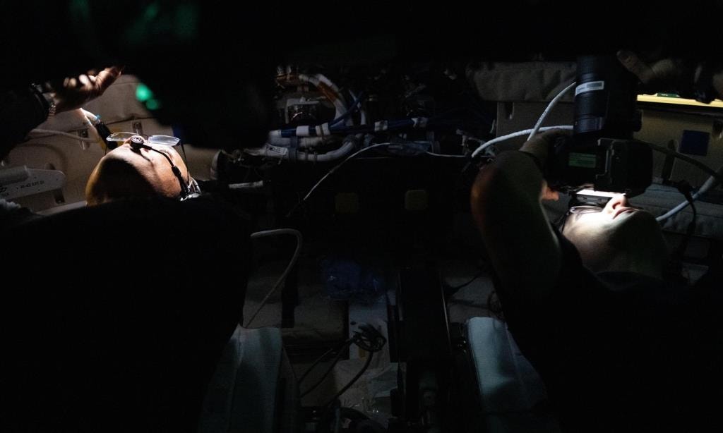  O piloto da Artemis II, Victor Glover, e a especialista de miss&atilde;o Christina Koch recolhem imagens e observam a superf&iacute;cie lunar para depois compartilhar com o mundo durante o sobrevoo lunar no sexto dia da miss&atilde;o. A tripula&ccedil;&atilde;o passou aproximadamente sete horas a trocar de lugar juntos &agrave;s pequenas escotilhas da Orion enquanto sobrevoavam o lado oculto da Lua. No ponto de maior aproxima&ccedil;&atilde;o, eles chegaram a estar a 6.547 quil&oacute;metros da superf&iacute;cie lunar. Cr&eacute;dito: NASA 