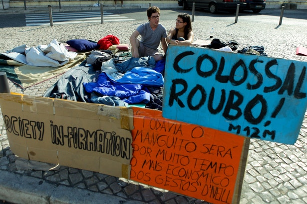  Entre sacos-cama e cartazes, um par de manifestantes monta "acampamento" diante da Assembleia da Rep&uacute;blica (fotografia: Miguel A. Lopes, Lusa) 