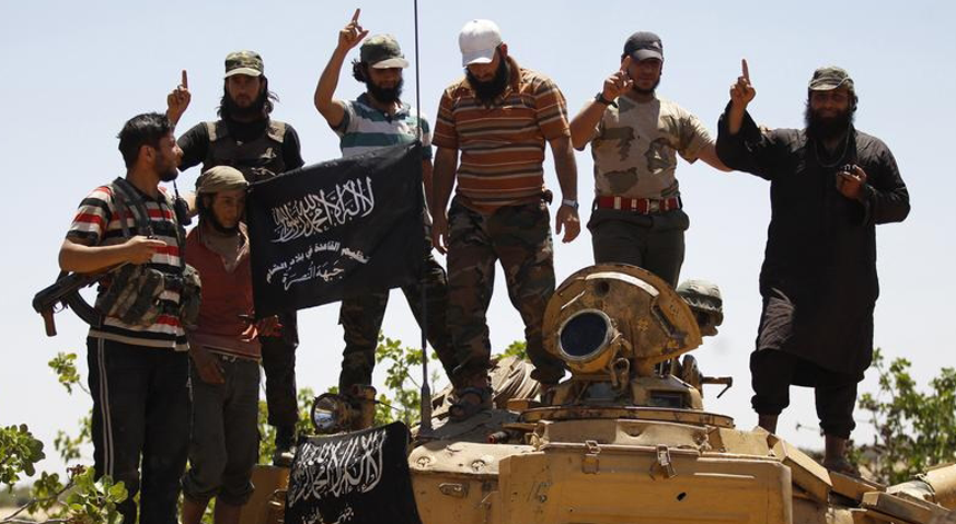 Membros da Frente al-Nusra, grupo islamita filiado na al-Quaeda festejam em cima de um tanque na frente de combate de Al-Khazan, a norte da província síria de Idlib, em maio de 2014
