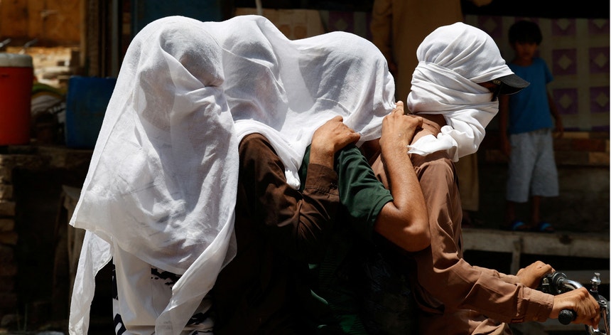 Durante a onda de calor as pessoas que circulam de moto cobrem a cabeça com um pano húmido para se refrescar e evitar a luz solar, em Jacobabad.
