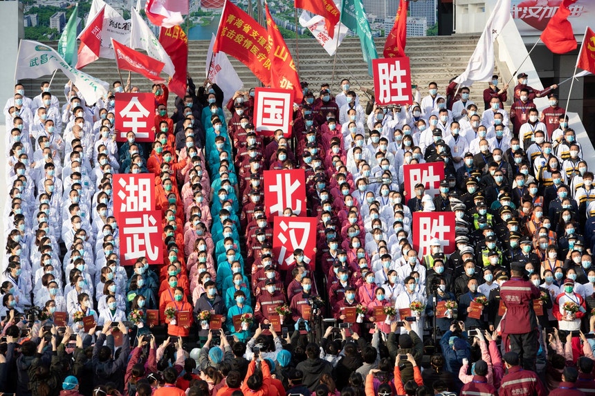 Pessoal médico e de enfermagem, de máscara, posa para uma fotografia durante a cerimónia de encerramento do último hospital improvisado em Hubei, a 10 de março de 2020. As faixas dizem "Vitória do país, vitória de Hubei, vitória de Wuhan"
