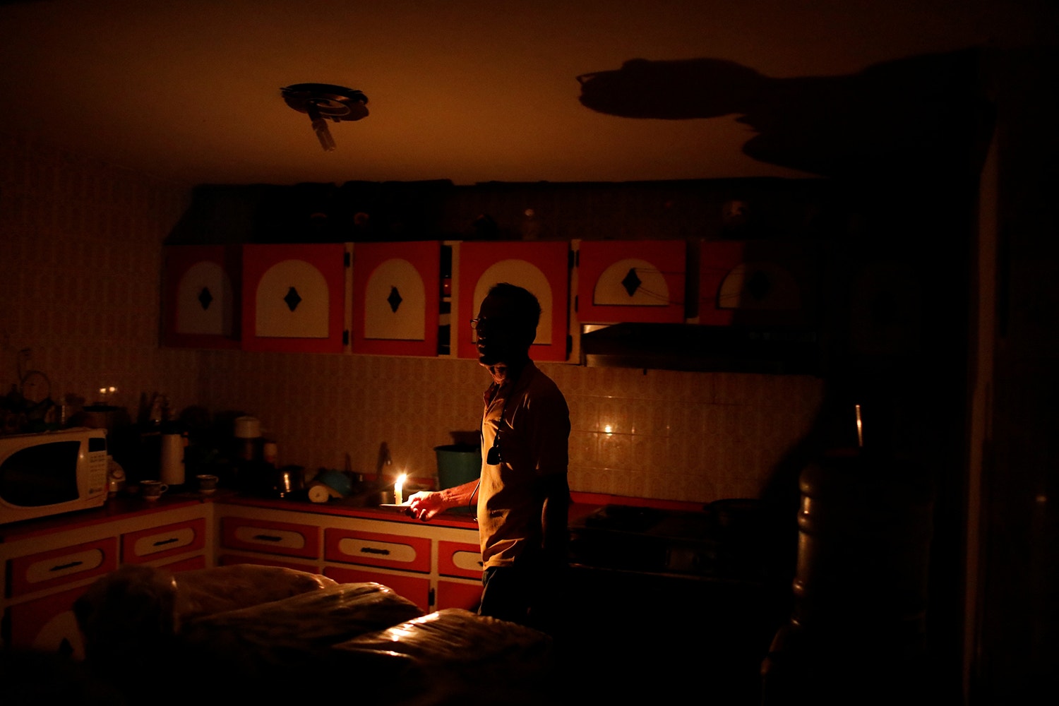  Americo Fernandez utiliza uma vela para iluminar a sua casa /Foto: /Marco Bello - Reuters 