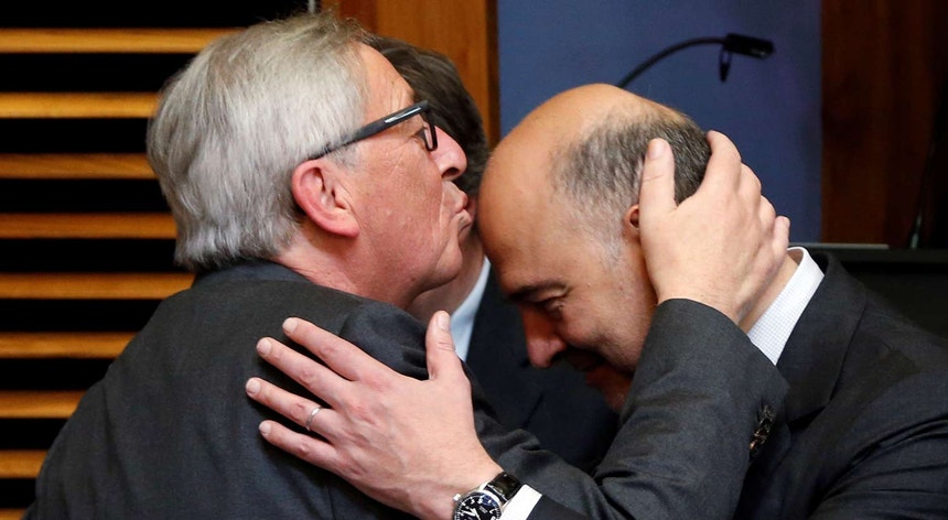 Juncker cumprimenta o comissário europeu das Finanças, Pierre Moscovici (à esq.)
